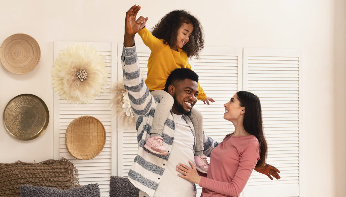 International family have fun. Father holds daughter on shoulders